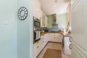 a kitchen with white cabinets and a clock on the wall at 4 Bed House Mapperley walking distance to city centre Nottingham sleeps 8 in Nottingham