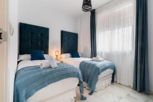 2 letti in una camera con blu e bianco di Apartamentos Cruz de San Andrés a Siviglia