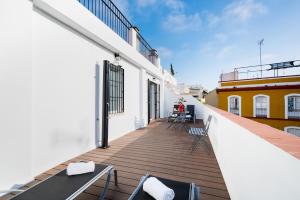 un balcone con sedie e tavoli su un edificio di Apartamentos Cruz de San Andrés a Siviglia