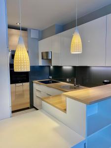 een keuken met witte kasten en twee hanglampen bij Project Comfort Apartament Przasnyska 7/33 Warszawa in Warschau