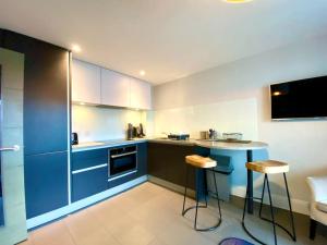 a kitchen with blue cabinets and a table and stools at Stunning Apartment - 1 Minute walk to Poole Quay - Great Location - Free Parking - Fast WiFi - Smart TV - Newly decorated - sleeps up to 2! Close to Poole & Bournemouth & Sandbanks in Poole
