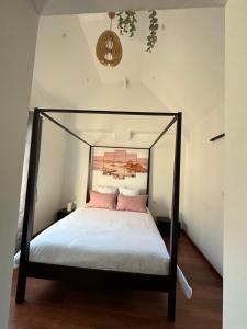 um quarto com uma cama de dossel preta com almofadas cor-de-rosa em La suite Brésilienne em Forges-les-Eaux