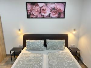 um quarto com uma cama com duas mesas e uma imagem na parede em Attila Studio Apartments em Hajdúszoboszló