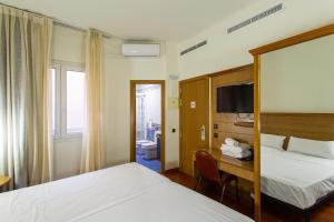 una camera d'albergo con 2 letti, una scrivania e una TV di Negresco Gran Via a Madrid
