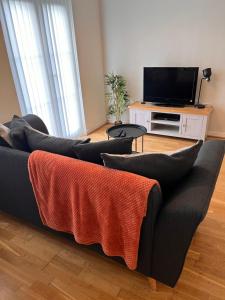 sala de estar con sofá negro y TV en At home in the city serviced apartments Newport, en Newport