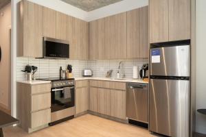 uma cozinha com armários de madeira e um frigorífico de aço inoxidável em Kasa River North Chicago em Chicago