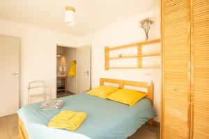 Gite Le Rucher في لانس-آن-فيركور: غرفة نوم عليها سرير وفوط صفراء