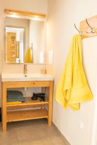 La salle de bains est pourvue d'un lavabo et d'une serviette jaune. dans l'établissement Gite Le Rucher, à Lans-en-Vercors