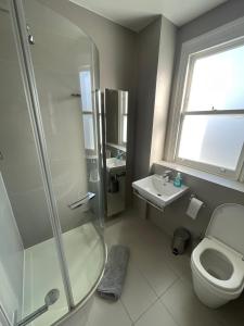 y baño con ducha, aseo y lavamanos. en Beautiful 4B.2Ba House + office en Raynes Park