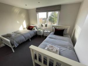 1 dormitorio con 2 camas y ventana en Beautiful 4B.2Ba House + office en Raynes Park