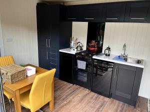 a kitchen with black cabinets and a wooden table and a table and chairs at Pine Boutique Lodge with hot tub for couples & dog in York