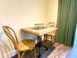 a wooden table with two chairs and a green curtain at Stylish Apartment - 1 Minute walk to Poole Quay - Great Location - Free Parking - Fast WiFi - Smart TV - Newly decorated - sleeps up to 2! Close to Poole & Bournemouth & Sandbanks in Poole