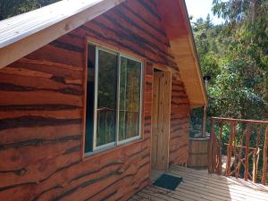 eine Blockhütte mit einer Veranda und einem Fenster in der Unterkunft Refugio y Tinaja Curiñanco in Valdivia