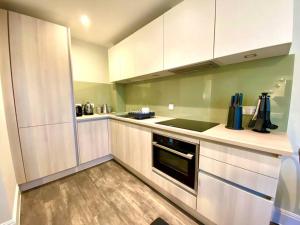 a kitchen with white cabinets and a stove at Stylish Apartment - 1 Minute walk to Poole Quay - Great Location - Free Parking - Fast WiFi - Smart TV - Newly decorated - sleeps up to 2! Close to Poole & Bournemouth & Sandbanks in Poole