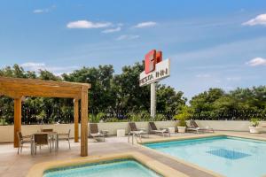 a pool at a hotel with a pool inn sign and chairs at Fiesta Inn Guadalajara Expo in Guadalajara