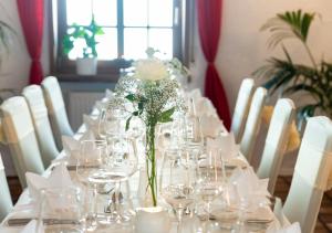 a long table with glasses and a vase of flowers at Hotel Rosenhof GmbH in Ramstein-Miesenbach
