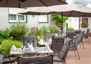 un restaurante al aire libre con mesas, sillas y sombrillas en Hotel Rosenhof GmbH en Ramstein-Miesenbach