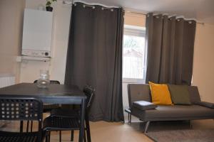 a living room with a table and a couch and a window at London 4 Bedroom House in London