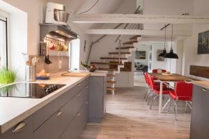 a kitchen with red chairs and a wooden table at Reetdachhaus, Sauna, E-Bikes, 6 Personen in Osterhever