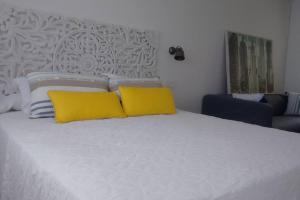 Una cama blanca con dos almohadas amarillas. en Estudio 2 PAX 140 m playa Caneliñas, (403), en Sanxenxo