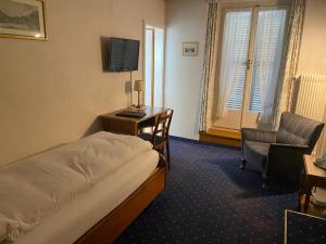 a hotel room with a bed and a desk and a television at Hotel Du Lac in Interlaken