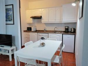 a kitchen with white cabinets and a white table and chairs at Casa Alisios in Playa de Santiago