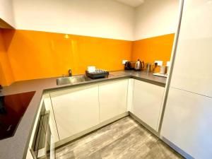 a kitchen with orange and white cabinets and a sink at Luxurious Studio Apartment - 1 Minute walk to Poole Quay - Great Location - Free Parking - Fast WiFi - Smart TV - Newly decorated - sleeps up to 2! Close to Poole & Bournemouth & Sandbanks in Poole