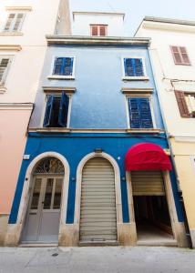 un edificio azul con dos puertas y un toldo rojo en Guesthouse Natalija, en Pula