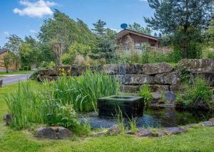 a garden with a pond and a stone wall at Ribblesdale Lodges in Gisburn