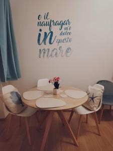 una mesa de comedor con sillas y un cartel en la pared en Triremi house en Lido di Ostia