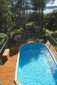 a large blue swimming pool on a wooden deck at Blue Gum Cottage on Bay in Bensville