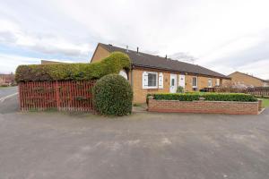 a house with a red fence and a hedge at Park Cottage in Scunthorpe