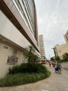 un edificio en una calle con gente caminando por una acera en Praia Grande (12) - 3 quartos - 1 quadra Mar, en Torres