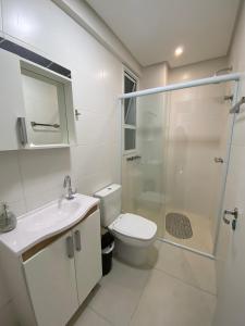 a bathroom with a toilet and a shower and a sink at Praia Grande (12) - 3 quartos - 1 quadra Mar in Torres