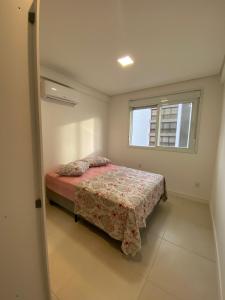 a small bedroom with a bed and a window at Praia Grande (12) - 3 quartos - 1 quadra Mar in Torres