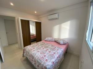 1 dormitorio con 1 cama con manta rosa y almohadas en Praia Grande (12) - 3 quartos - 1 quadra Mar, en Torres