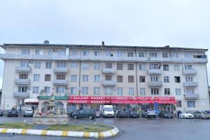 a large white building with cars parked in a parking lot at Sweet Home in Kutaisi