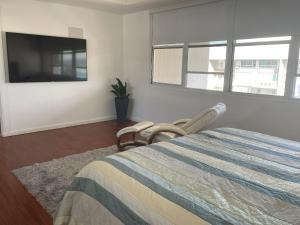 Schlafzimmer mit einem Bett und einem Flachbild-TV in der Unterkunft 2 Bedrooms 2 Bathrooms Beach Front Apt @ Coral in San Juan