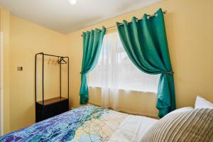 um quarto com uma cama e uma janela com cortinas verdes em Three Bed Luxury Home in London em Abbey Wood