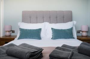 sypialnia z dużym białym łóżkiem z zielonymi poduszkami w obiekcie Cherry Tree Villa w mieście Harrogate