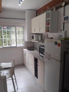 eine Küche mit weißen Schränken und einem weißen Kühlschrank in der Unterkunft PARQUE LELOIR, ITUZAINGO in Villa Leloir