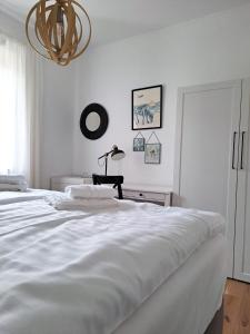 ein weißes Schlafzimmer mit einem Bett und einem Kronleuchter in der Unterkunft Quartier35 