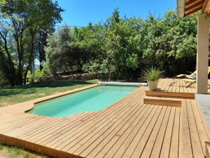 a pool with a wooden deck next to a backyard at Charmante maison à Payzac avec piscine privée et Clim in Payzac