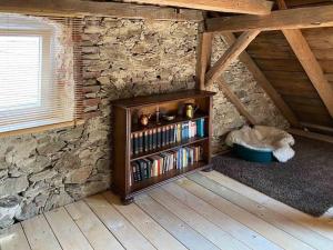 ein Bücherregal in einem Zimmer mit einer Steinmauer in der Unterkunft Denkmalgeschützter Bauernhof in Schauenstein