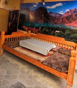 Ce lit en bois se trouve dans une chambre ornée d'une peinture murale. dans l'établissement ALI HOSTEL, à Douchanbé