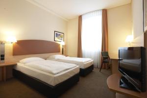 a hotel room with two beds and a flat screen tv at IntercityHotel Berlin Ostbahnhof in Berlin