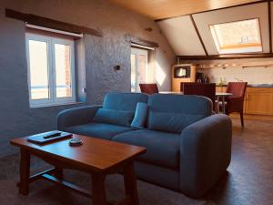 - un salon avec un canapé bleu et une table dans l'établissement Appart Hotel Au Pied de Vigne, à Vresse-sur-Semois