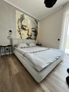 a bedroom with a large white bed with a painting on the wall at Silesia Apartments Ustron H125 in Ustroń