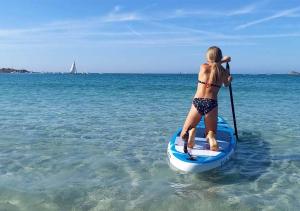 une femme est debout sur une planche de paddle dans l'eau dans l'établissement LES PORTSALLAISES piscine ou spa à 300m de la plage, à Ploudalmézeau