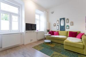 a living room with a yellow couch and a tv at Danube Art Apartments in Vienna